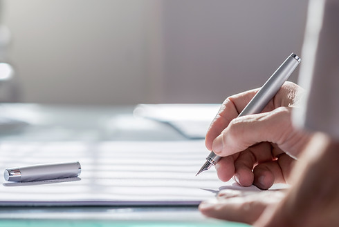 hand with pen writing on paper