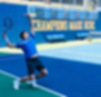 Bild eines Tennisspielers auf einem blauen Tennisplatz, der einen Aufschlag ausführt, mit einer beeindruckenden Körperhaltung