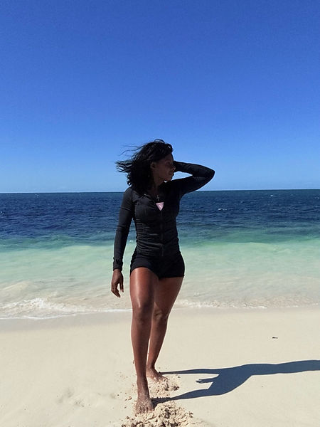 alt="Author Diana McKay stands thoughtfully on a serene beach, reflecting on inner peace and quiet strength.