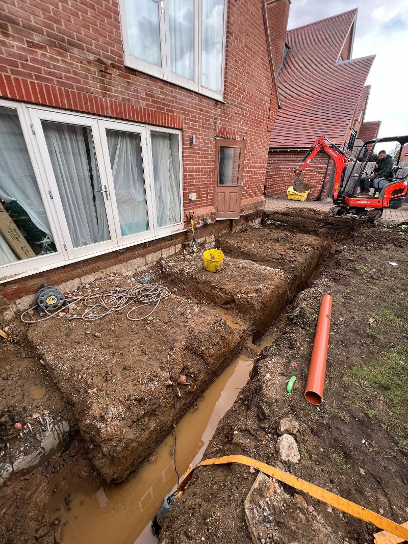 A digger removes soil from the ground at the rear of the property