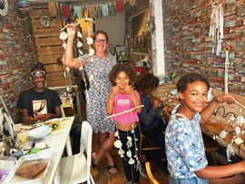 Family making shell crafts, smiling at a workshop.