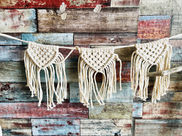 Three macrame banners against a rustic wood wall