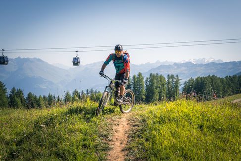 Cycliste descendant une piste, montagnes en arrière-plan
