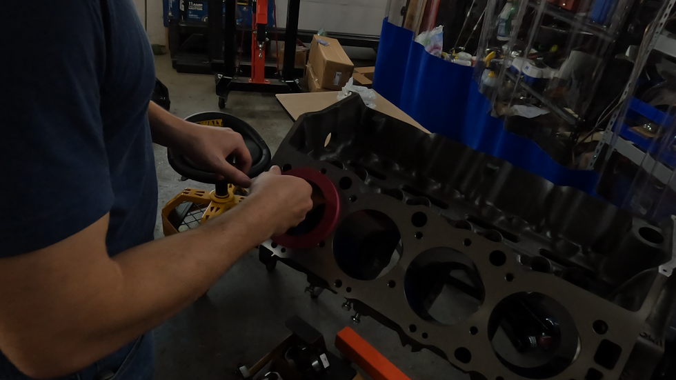 Custom piston ring squaring tool being used in a V8 engine block to position a piston ring for accurate end gap measurement during engine assembly