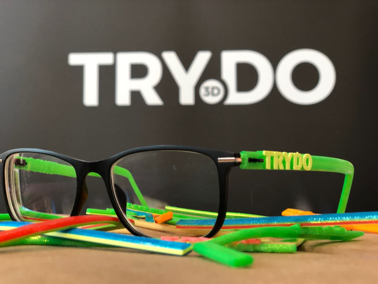 3D gedruckte Brille mit Trydo Logo im Hintergrund