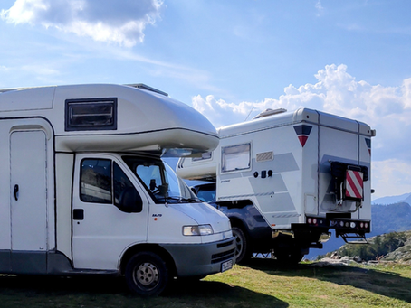 Zwei Wohnmobile stehen beim Freistehen dicht nebeneinander in einer Berglandschaft.
