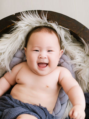 a laughing baby laying on a furry rug