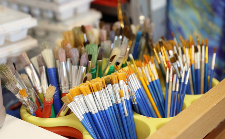 Various paint brushes in a yellow organizer for art class projects