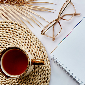 A cup of tea, glasses and a writing pad