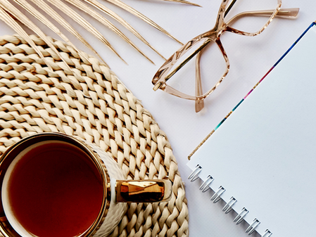A cup of tea, glasses and a writing pad