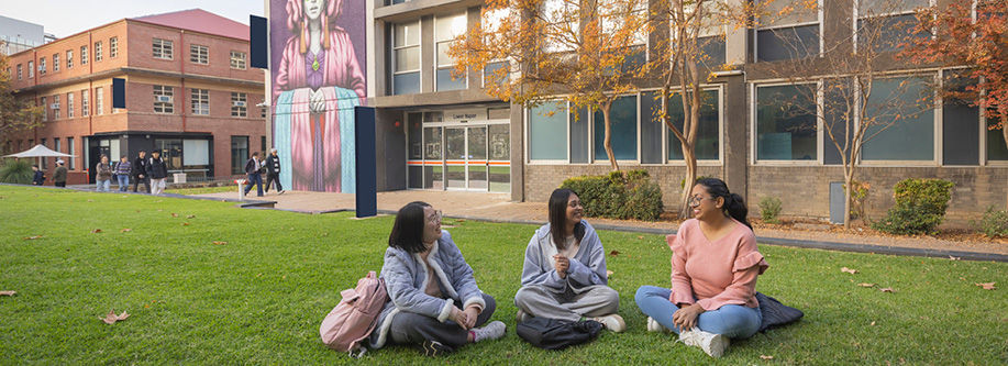 Three students sitting on grass