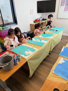 Students engaged in a group painting activity during an art class at Intelligent Learning California.