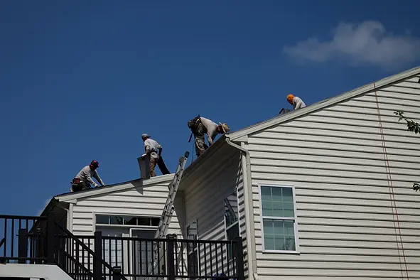 roofing-crew-working-on-a-house-installing-new-shingles-under-a-clear-blue-sky-with-ladder