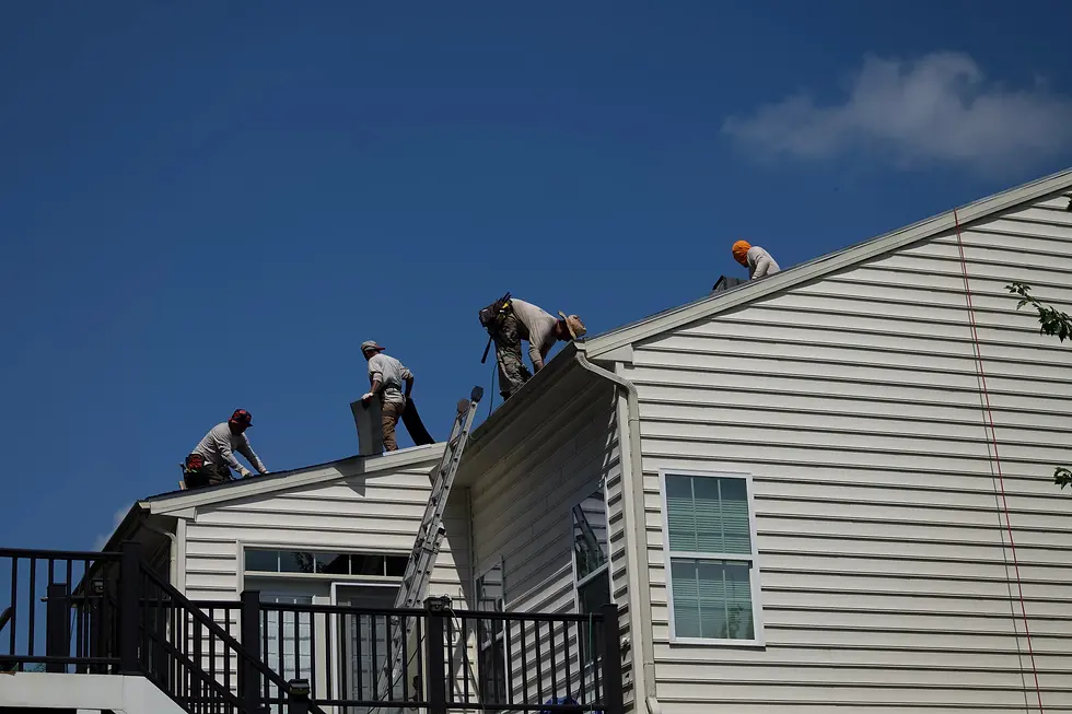 roofing-crew-working-on-a-house-installing-new-shingles-under-a-clear-blue-sky-with-ladders-and-safety-equipment-visible
