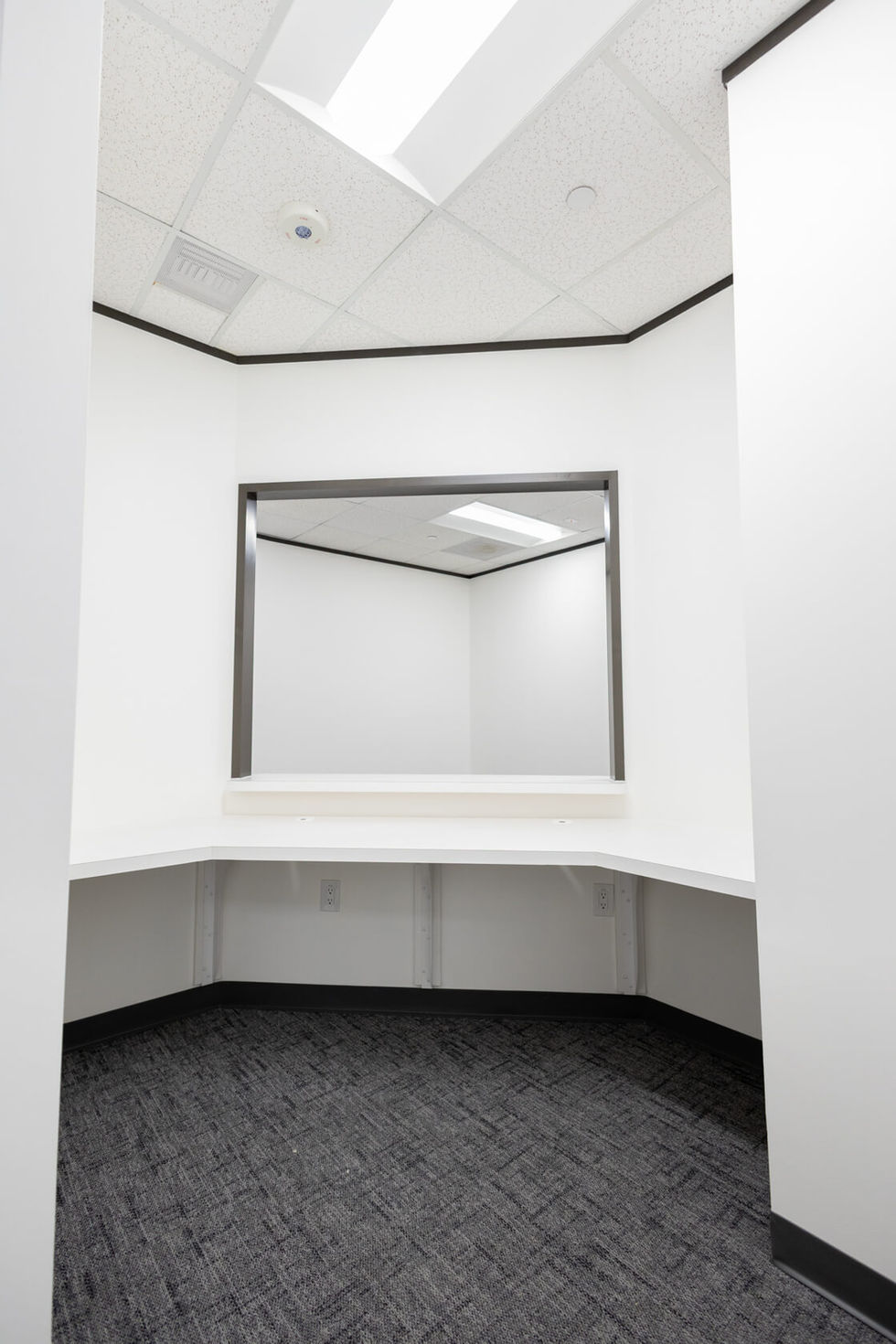 Minimalist white receptionist area with corner desk and window.