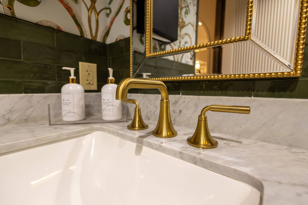 Gold faucet and soap dispensers on marble countertop.