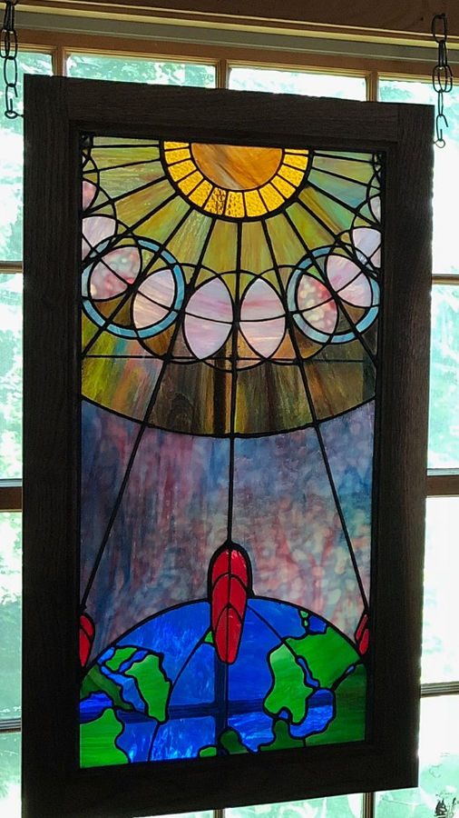 Framed custom stained glass panel by Higher Ground Design and Construction, featuring sun and earth motif