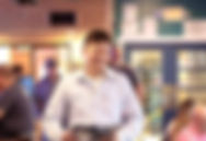 Employee walking and smiling with menus in hand