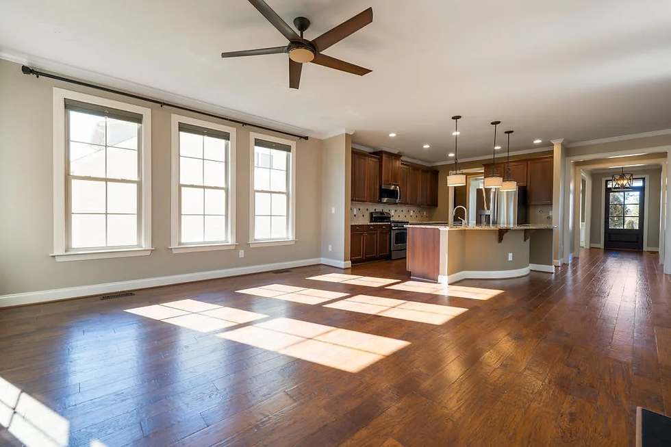 Spacious kitchen with wooden floors, island, brown cabinets, and stainless appliances. Sunlight streams through large UPVC windows onto the floors.