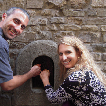 A man and woman knocking on a tiny wooden door outside a stone building in Florence Italy