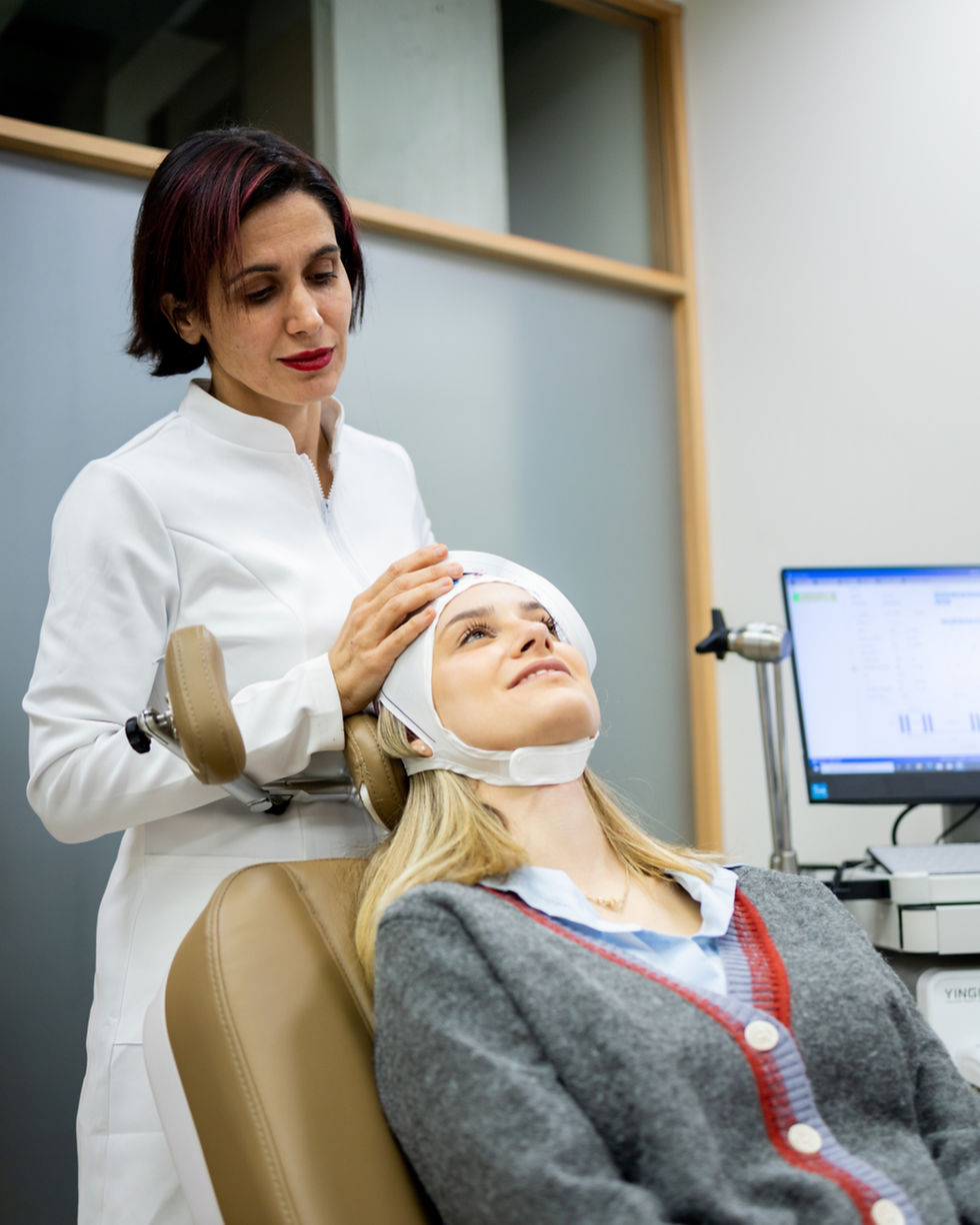 Vertical photo of an adult female psychiatrist is placing a transcranial magnetic stimulat
