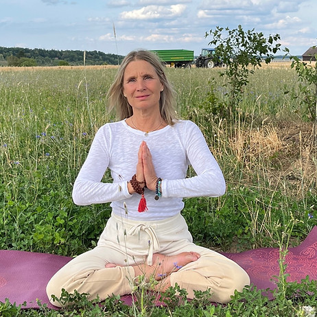 Barbara Miller auf einer Yogamatte in einem Feld