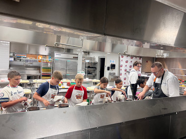 Chef Shawn and Instructor Rylan assist junior chefs in making their marinara sauce for their pizzas.