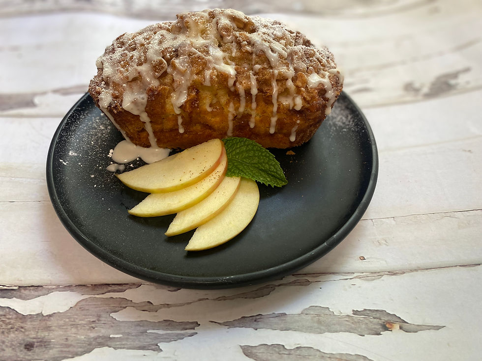 Amish Apple Fritter Bread drizzled with glaze and served with fresh apple slices and a mint garnish on a dark plate.