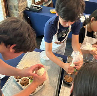 Junior chefs use special pipping tools to add their cream cheese filling to cinnamon roll muffins.