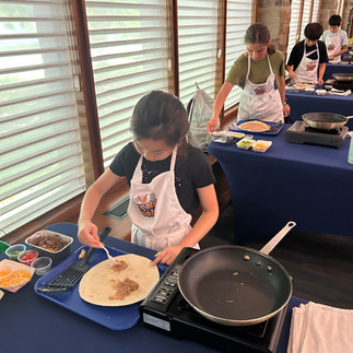 Junior chef layers ingredients for Breakfast Burrito.