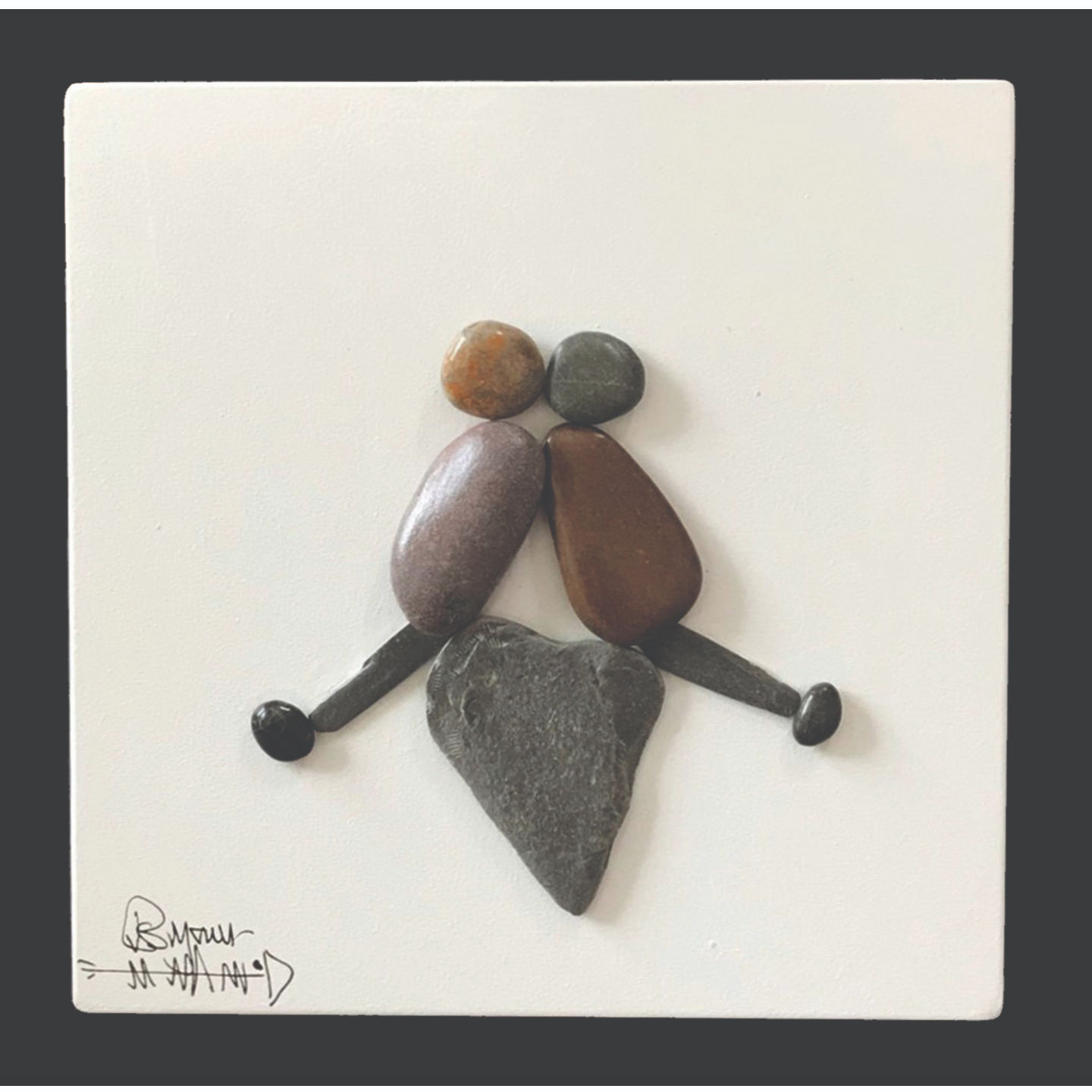 Pebble couple sitting on a pebble heart framed