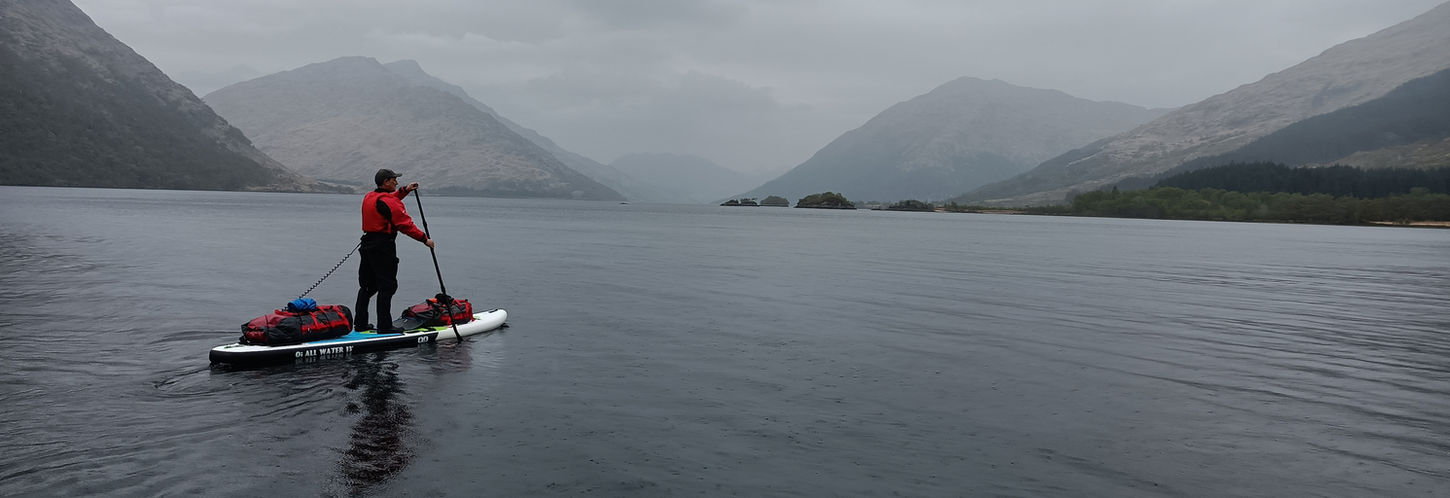 expedition paddle boarder in misty mountain loch