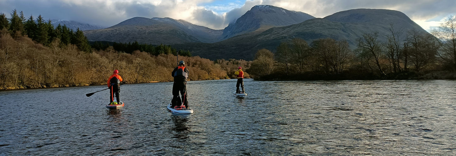 paddle boarder paddling with mountain in back ground 