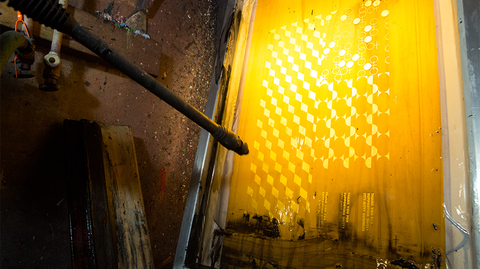 Process photo of a screen being cleaned with a pressure washer.