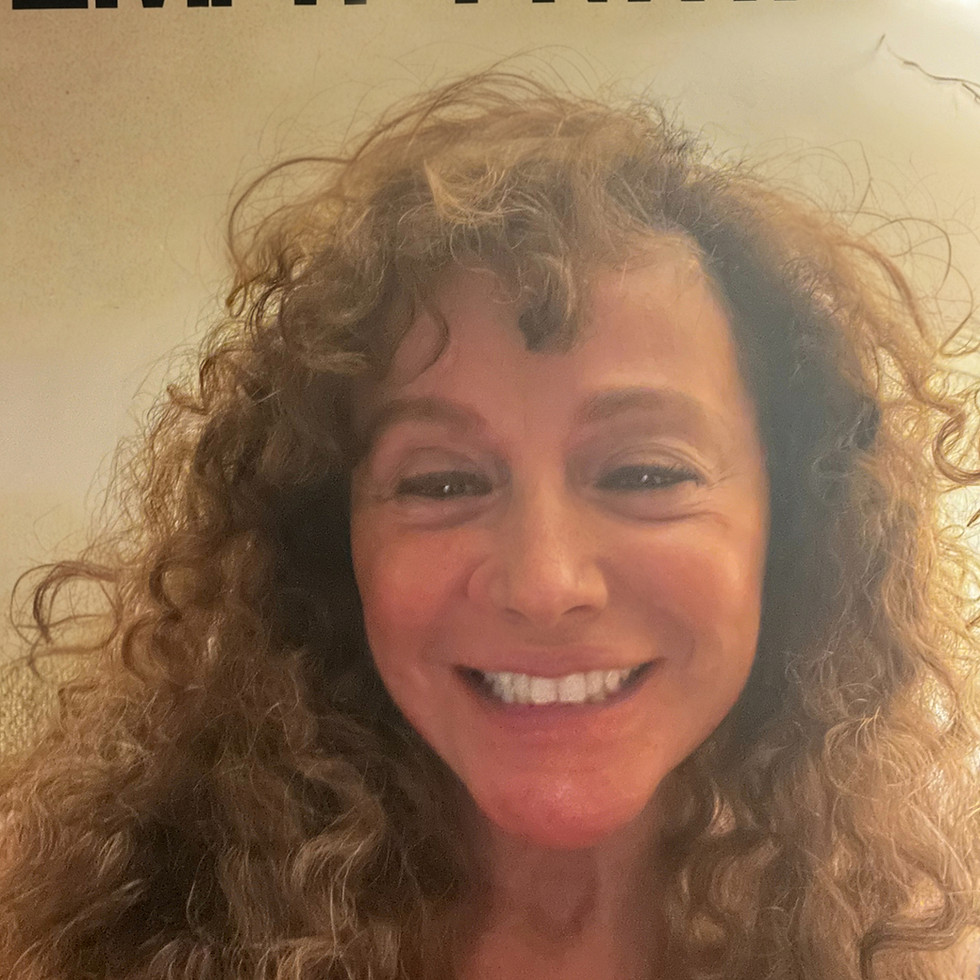 Smiling woman with curly hair offering online therapy Florida.