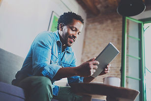 man sitting on the couch looking at tablet