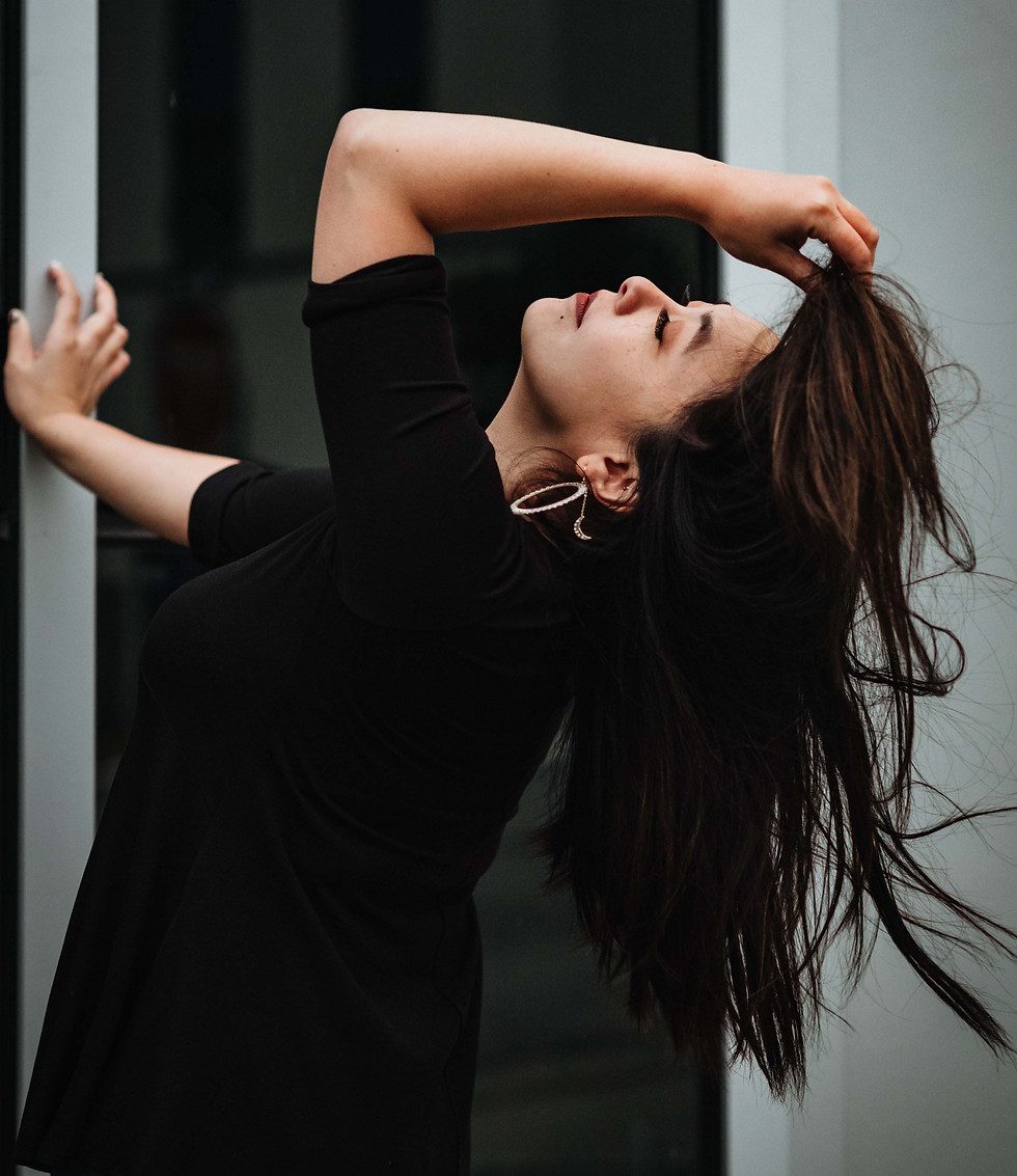 Rizza flipping hair and leaning against silver building.