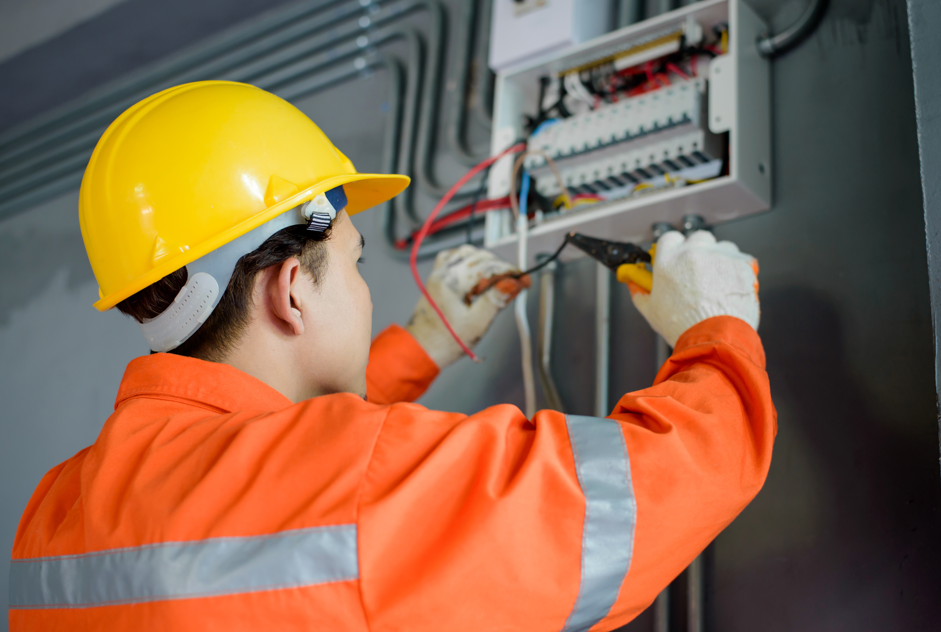 An elecrician performing reactive maintenance work on a fusebox
