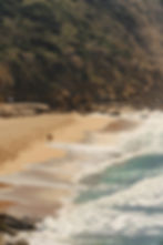A surfer walks along a windswept beach in Portugal