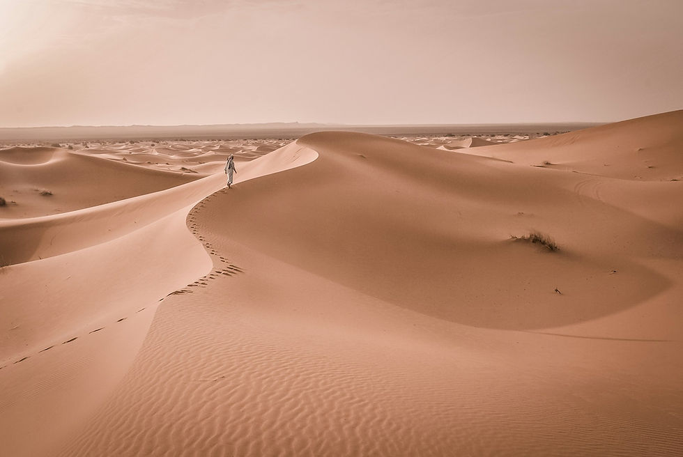 A Moroccan man walks across the dunes on a tour to the Sahara from Marrakech
