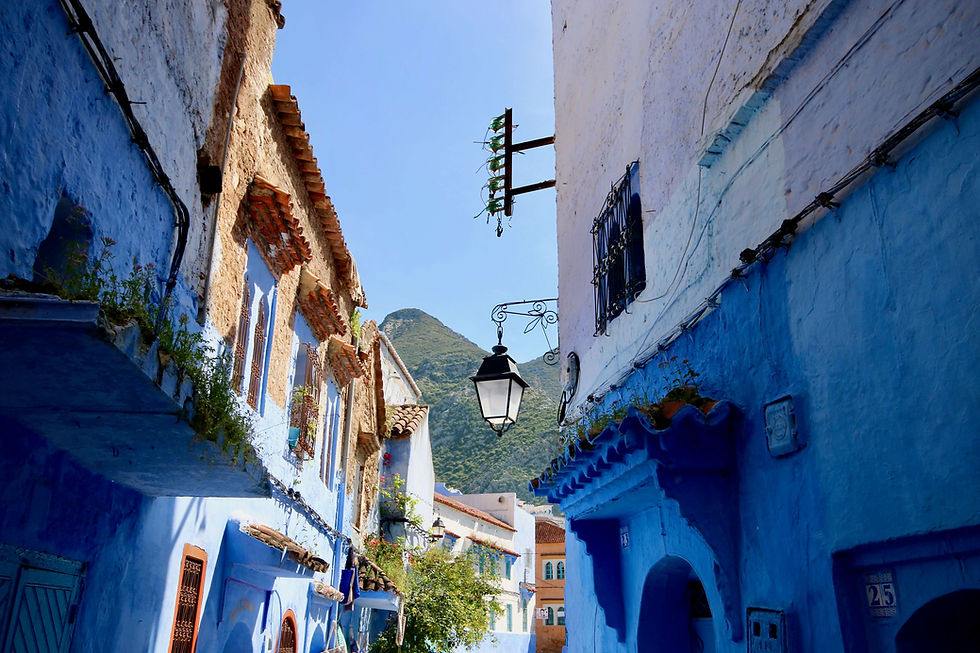 A blue-hued street in Chefchaouen, backed by the Rif Mountains