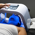 Woman lies under an led light mask during a facial treatment aimed at improving skin healt