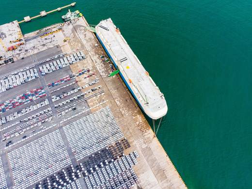 Aerial view of cargo ship docked at a European port with thousands of vehicles ready for transport