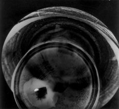Lids by Arthur Bruso Photogram of a circular, eye-like lens or glass disc with a dark center on a dark background