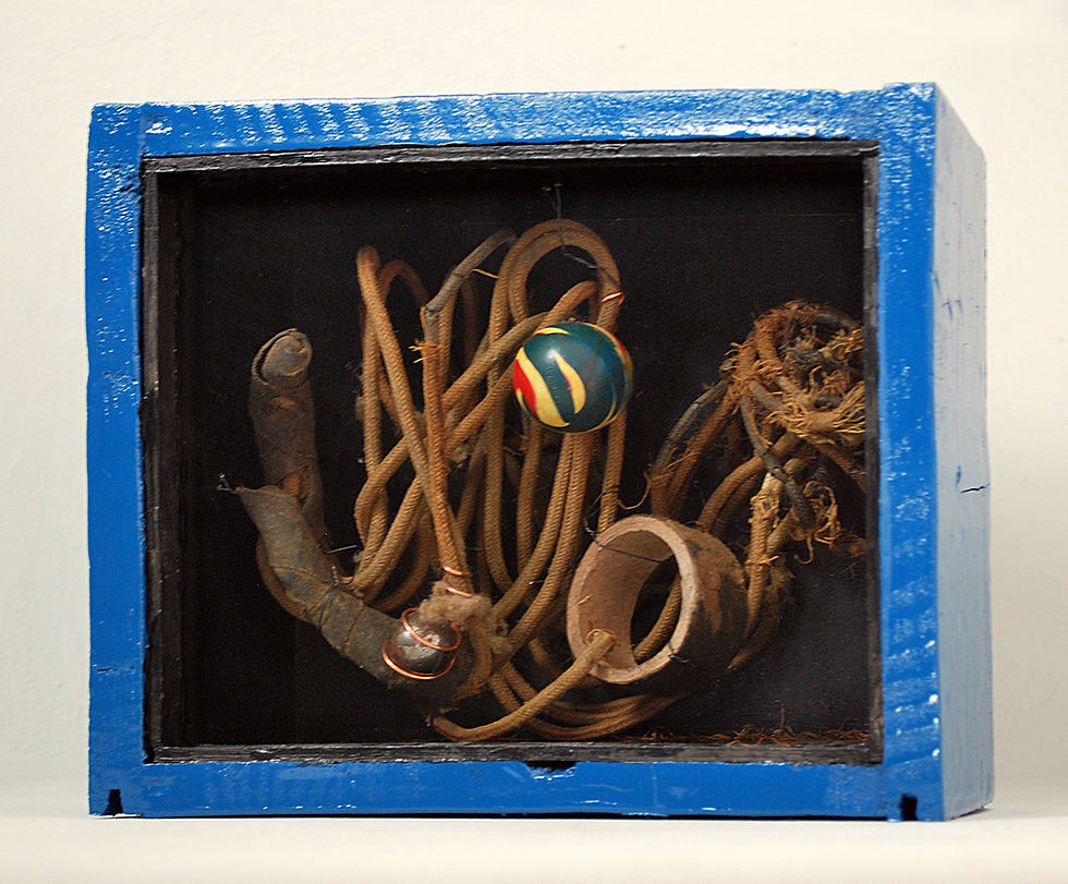 Dark Matter by Arthur Bruso. Blue shadow box with coiled wire, rusty metal scraps, and a small striped ball on a dark background.