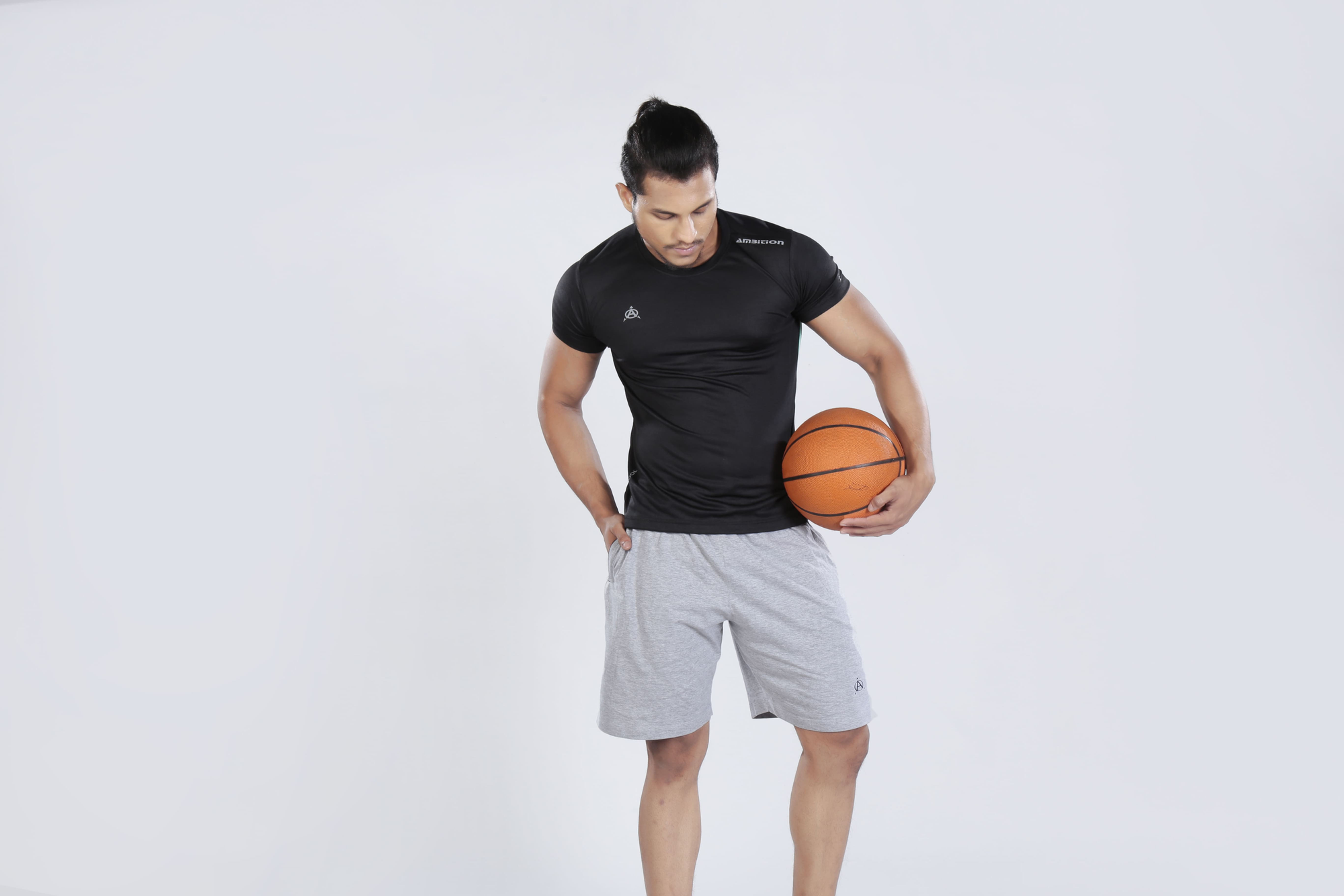 Man in black jersey and grey shorts holding basketball