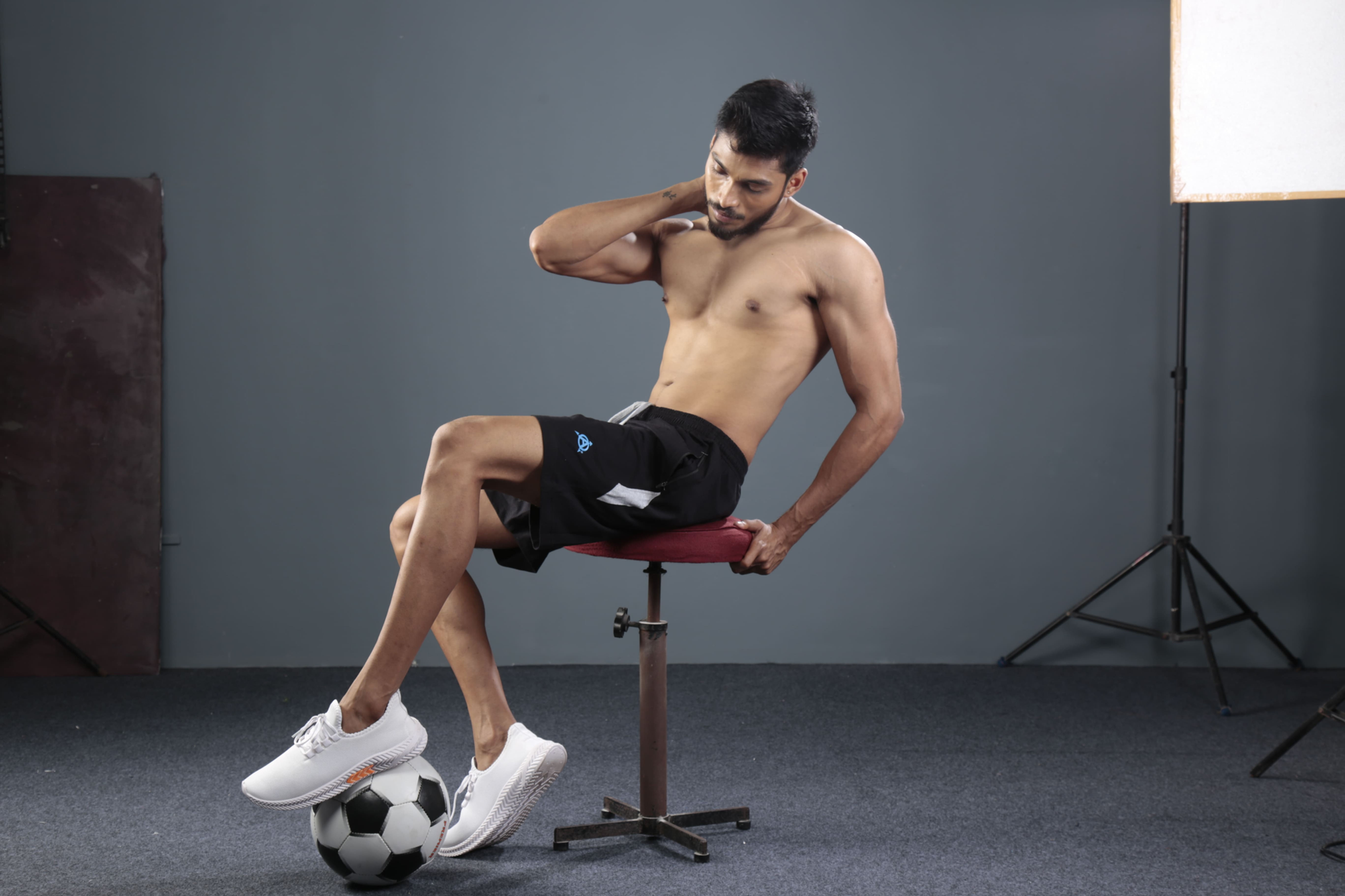 Man in athletic shorts seated with soccer ball