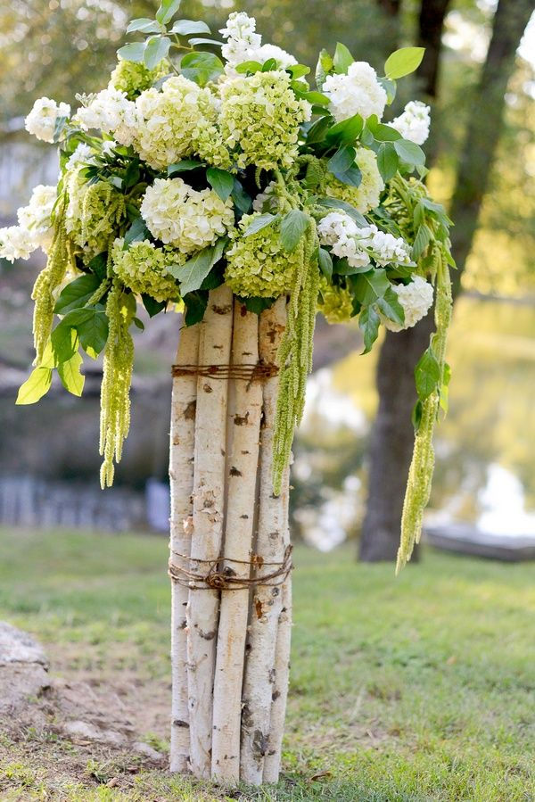 A stunning floral arrangement featuring vibrant orange and pink blooms, elegantly cascading over a rustic piece of driftwood, creating a perfect natural centerpiece for a wedding setting.