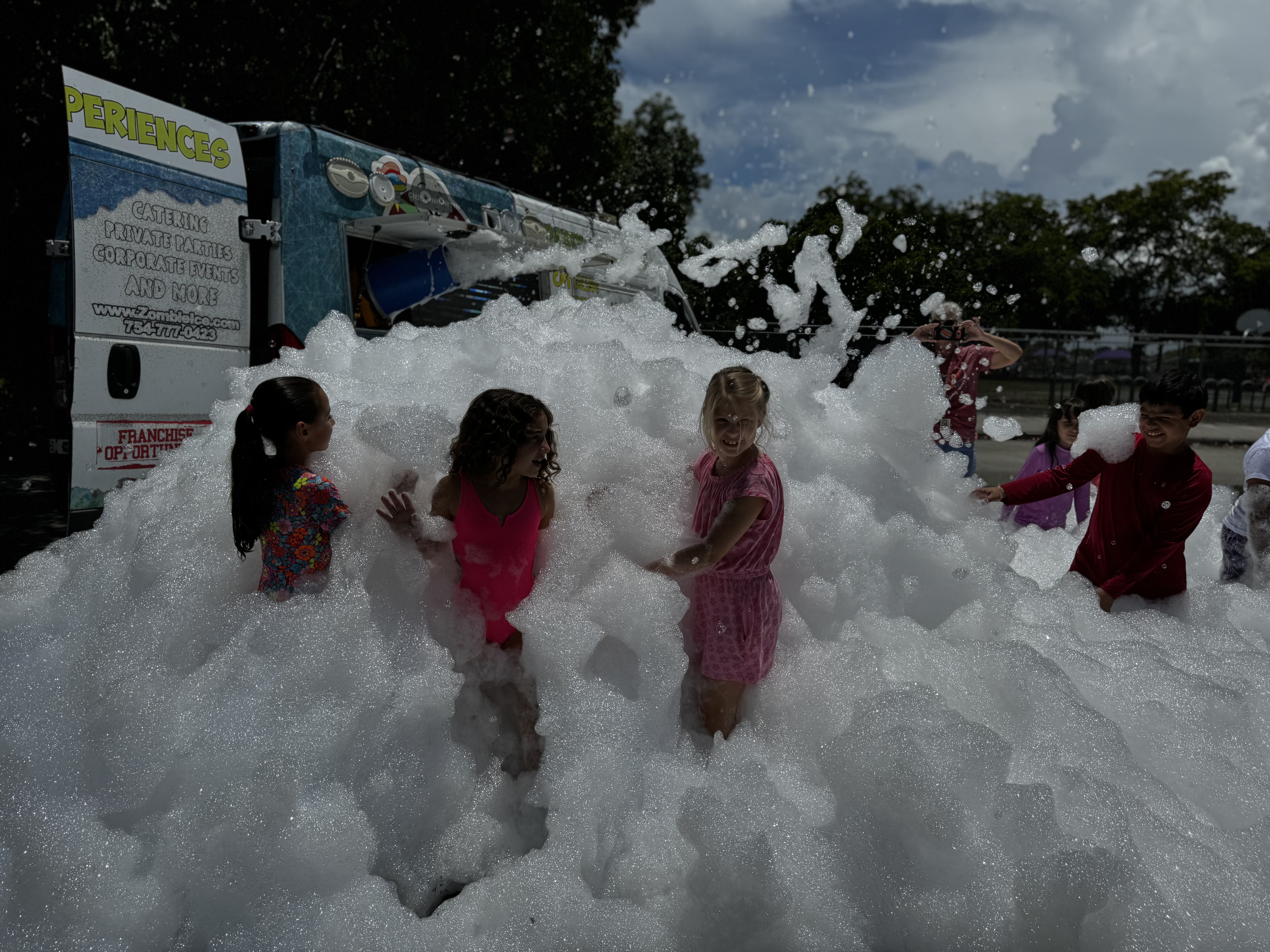 girls wearing pink playing on the bubbles or foam
