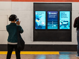 a train commuter takes a photograph of digital liveboards digital OOH of the advertiser Dataiku